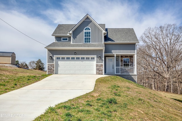 craftsman-style house with stone siding, driveway, an attached garage, and a front yard