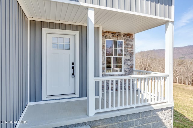 doorway to property with stone siding, covered porch, board and batten siding, and a mountain view