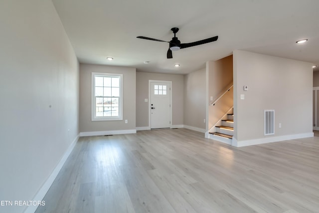 foyer entrance with visible vents, baseboards, ceiling fan, stairway, and light wood-style flooring