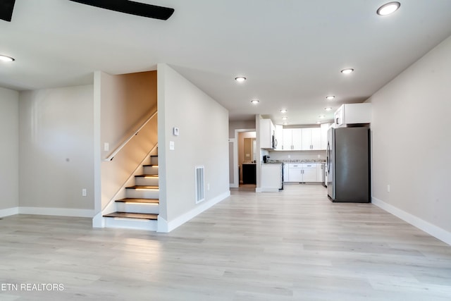 kitchen featuring visible vents, open floor plan, freestanding refrigerator, white cabinets, and light wood finished floors