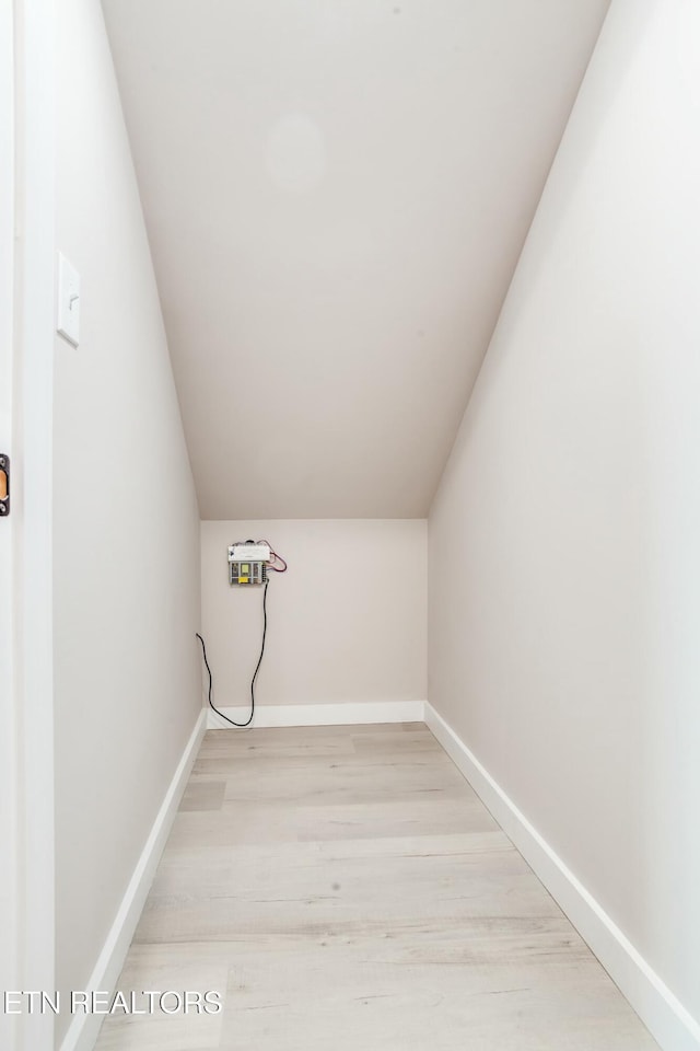 clothes washing area featuring baseboards and light wood-style floors