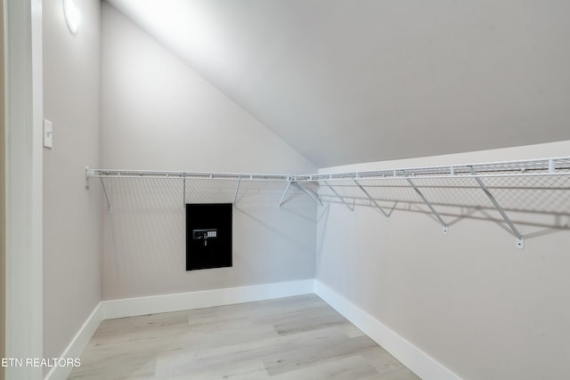 walk in closet featuring light wood-style floors and vaulted ceiling