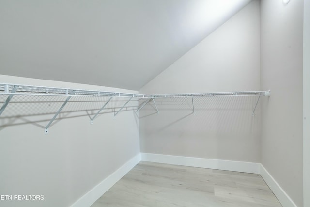 walk in closet with light wood-style flooring and vaulted ceiling