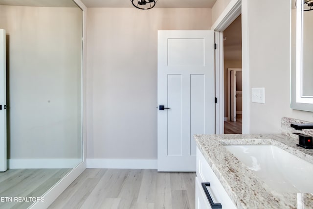 bathroom featuring vanity, wood finished floors, and baseboards