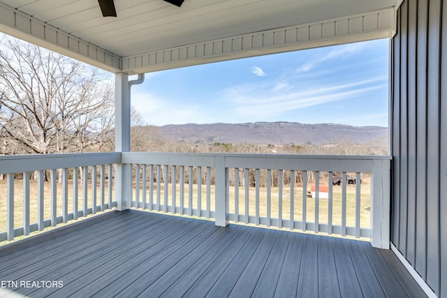 wooden terrace with a mountain view and a ceiling fan