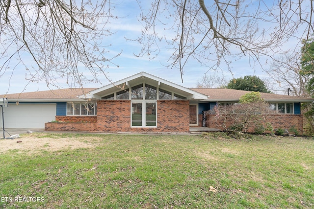 view of front of home featuring brick siding, an attached garage, and a front yard