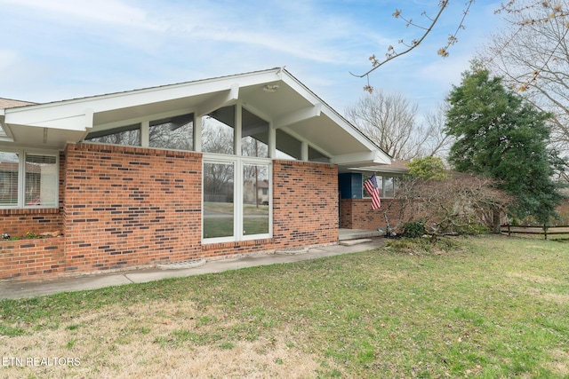 view of home's exterior with a lawn and brick siding