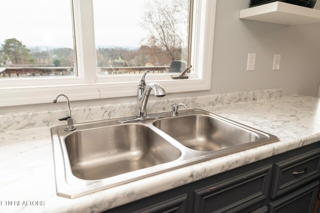 details with light stone countertops, dark cabinetry, and a sink