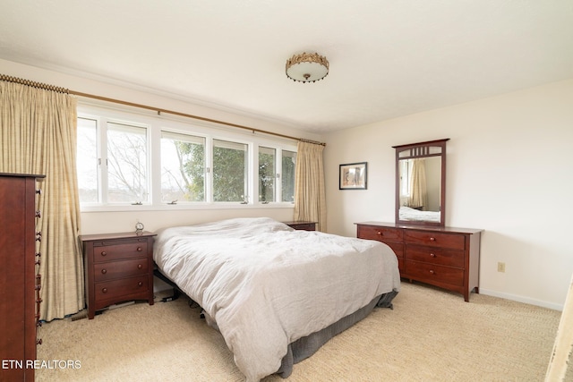 bedroom with light colored carpet, baseboards, and multiple windows