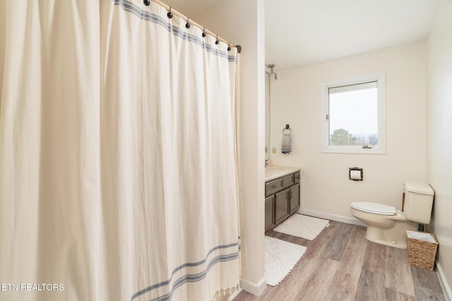 bathroom featuring vanity, toilet, wood finished floors, and baseboards