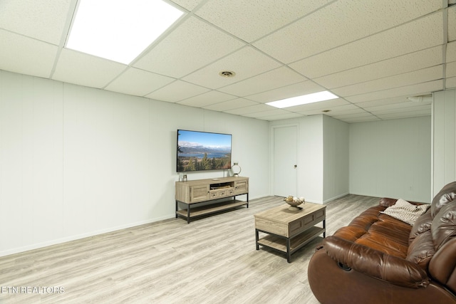 living room featuring a drop ceiling, visible vents, baseboards, and light wood-style floors