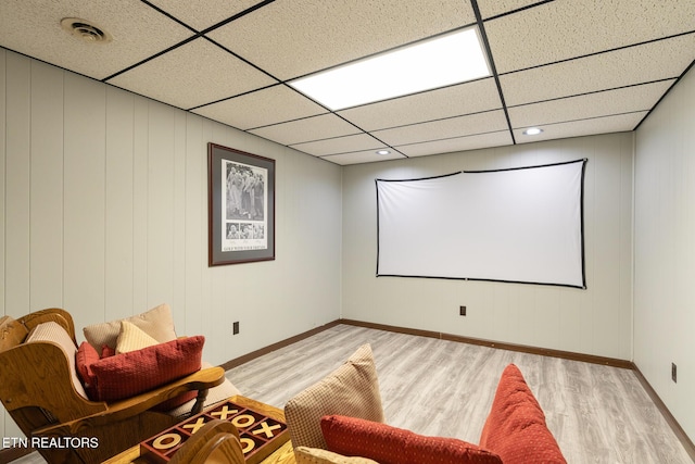 home theater featuring light wood-style flooring, a paneled ceiling, visible vents, and baseboards