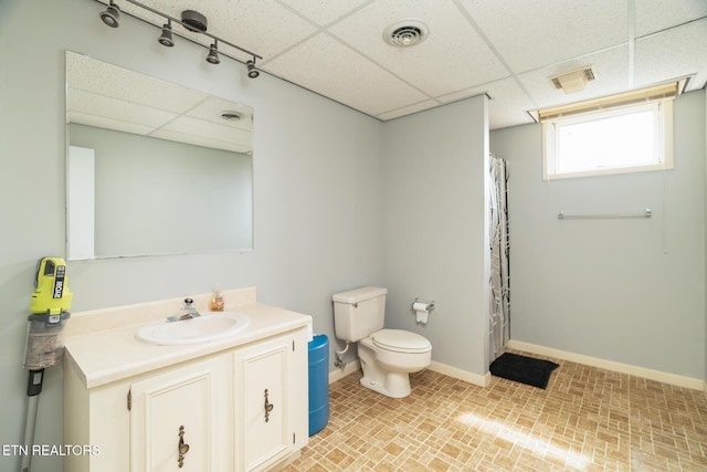 bathroom with visible vents, toilet, a paneled ceiling, and baseboards