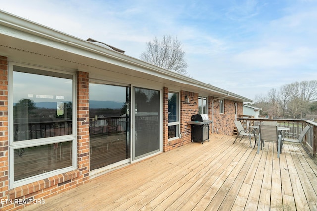 wooden deck featuring outdoor dining area and a grill