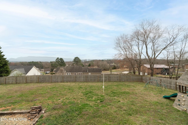 view of yard featuring a mountain view, a playground, and fence