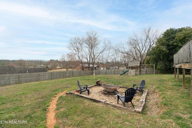 view of yard with a fire pit, a fenced backyard, and a playground