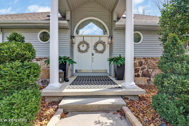 property entrance with stone siding and a shingled roof