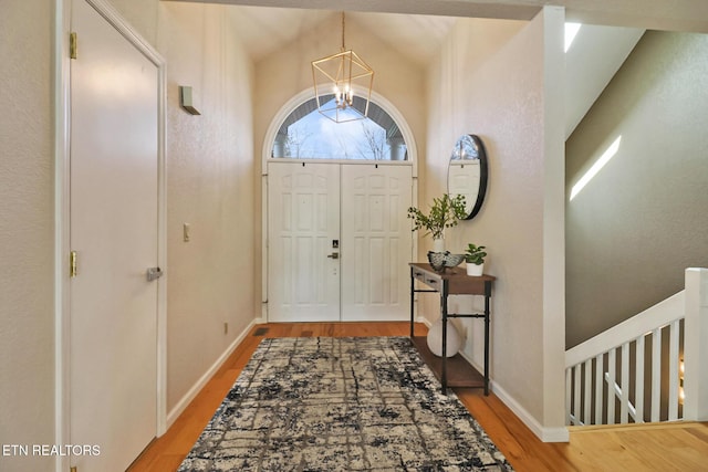 foyer featuring baseboards, a notable chandelier, and wood finished floors