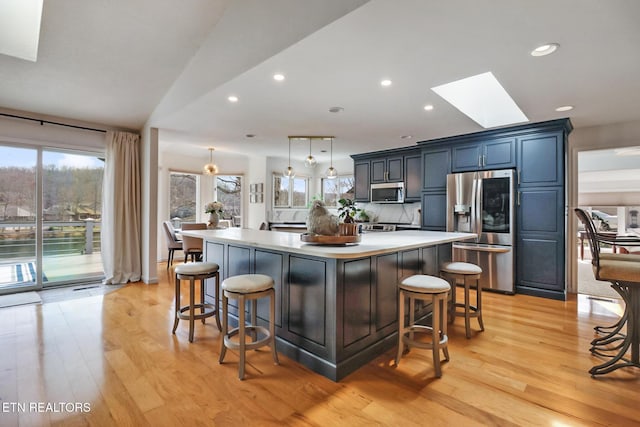 kitchen with a spacious island, a breakfast bar area, light countertops, a skylight, and stainless steel appliances