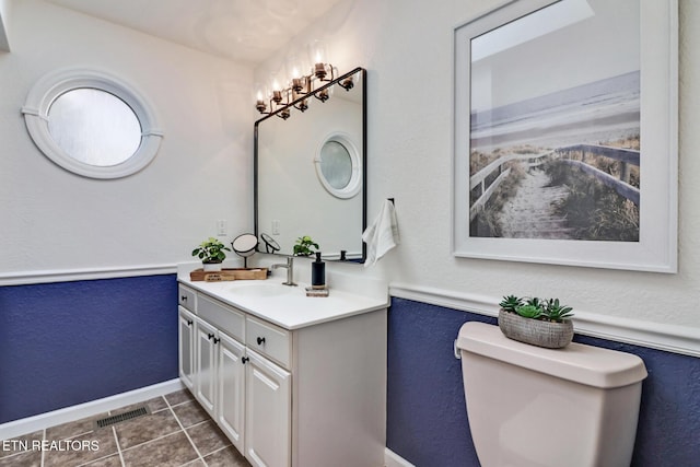 bathroom featuring visible vents, baseboards, toilet, tile patterned floors, and vanity