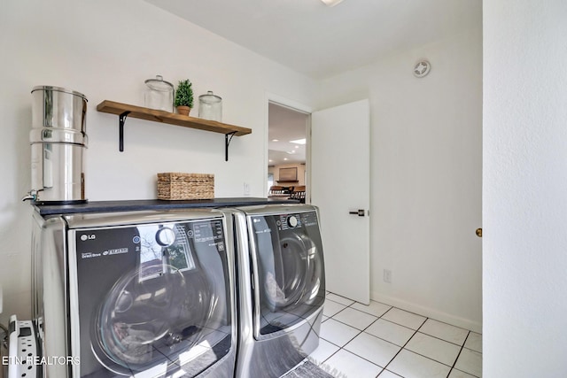 laundry room with laundry area, light tile patterned floors, and washing machine and clothes dryer