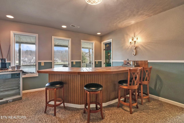 bar featuring a dry bar, baseboards, visible vents, and carpet floors