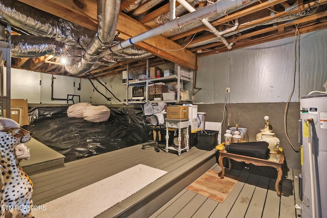 unfinished basement with electric water heater and hardwood / wood-style floors