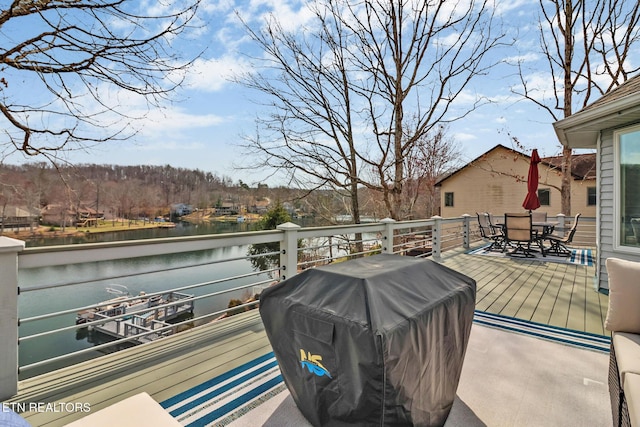 exterior space featuring outdoor dining area, a water view, and a grill