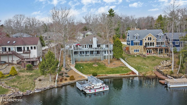 rear view of property with stairway, a lawn, a chimney, and a deck with water view