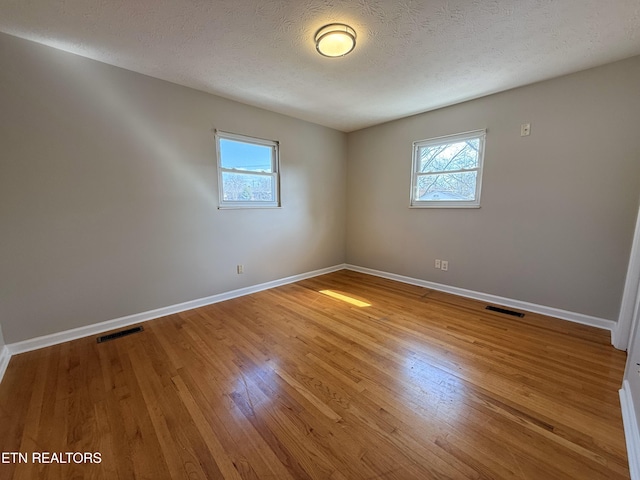 empty room featuring visible vents, baseboards, and hardwood / wood-style floors