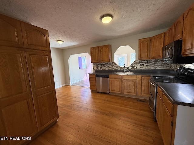 kitchen featuring light wood-style flooring, a sink, range with electric cooktop, black microwave, and stainless steel dishwasher