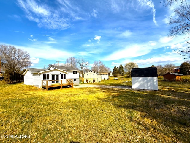 view of yard featuring a deck, an outbuilding, a shed, and driveway