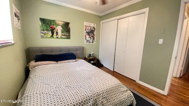 bedroom featuring wood finished floors, baseboards, ceiling fan, a closet, and crown molding