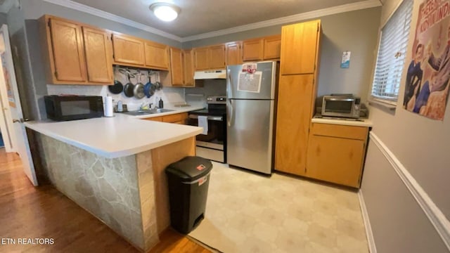 kitchen with a peninsula, ornamental molding, light countertops, under cabinet range hood, and appliances with stainless steel finishes