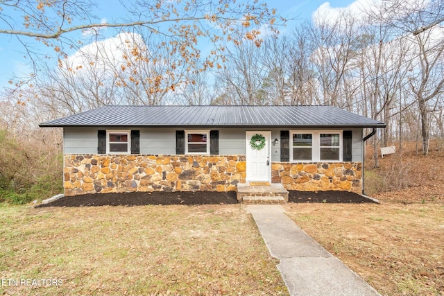 view of front of home featuring a front yard, stone siding, and metal roof