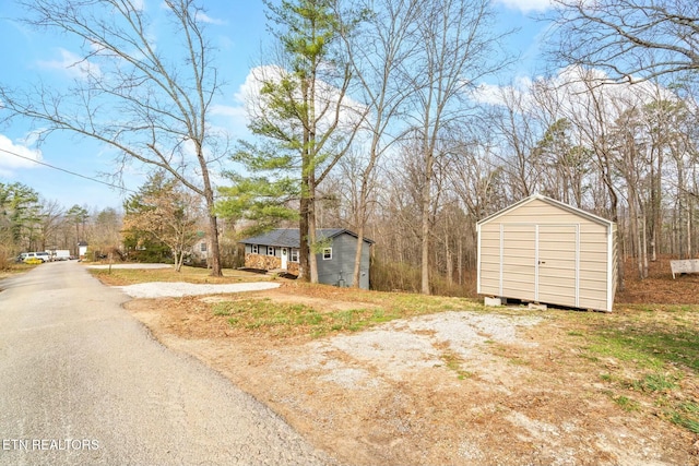 exterior space featuring aphalt driveway, an outbuilding, and a shed