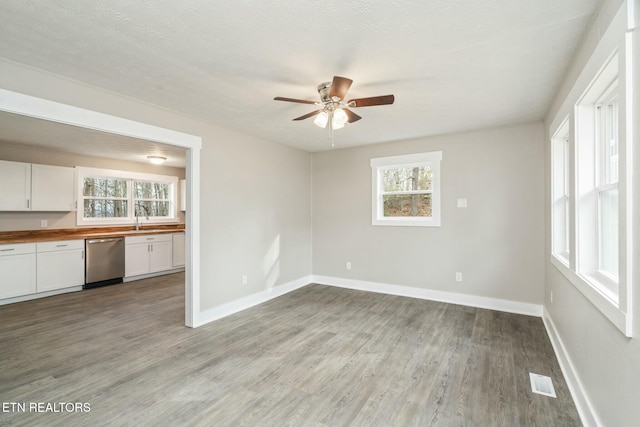 interior space with visible vents, a ceiling fan, a sink, light wood finished floors, and baseboards