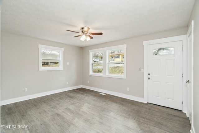 entrance foyer with baseboards, wood finished floors, visible vents, and ceiling fan