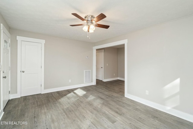 spare room with baseboards, wood finished floors, visible vents, and ceiling fan