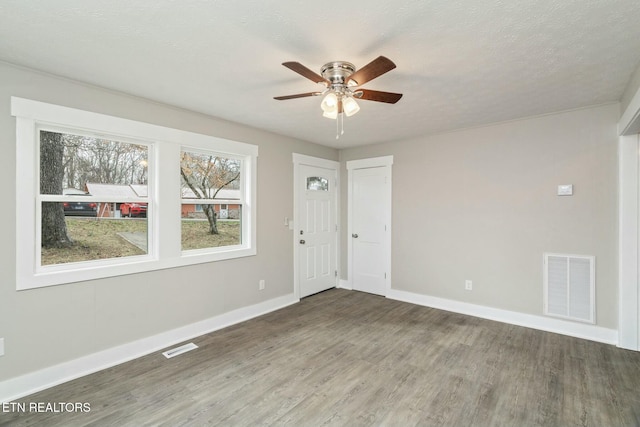 empty room featuring baseboards, wood finished floors, visible vents, and ceiling fan