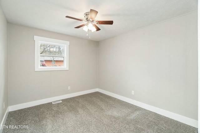 carpeted spare room with visible vents, baseboards, and ceiling fan