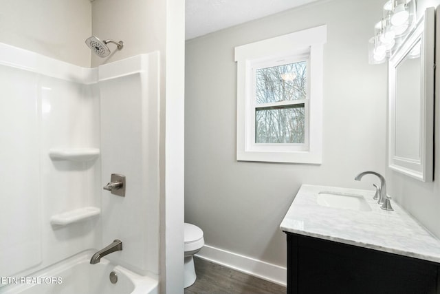 full bath with baseboards, shower / washtub combination, toilet, wood finished floors, and vanity