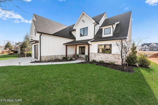 modern farmhouse featuring a front lawn, board and batten siding, an attached garage, and roof with shingles