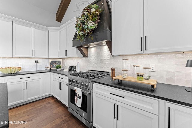 kitchen with dark countertops, dark wood finished floors, custom exhaust hood, white cabinetry, and high end stainless steel range