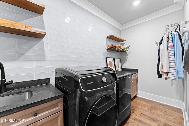 laundry area with cabinet space, a sink, crown molding, light wood-type flooring, and washer and clothes dryer