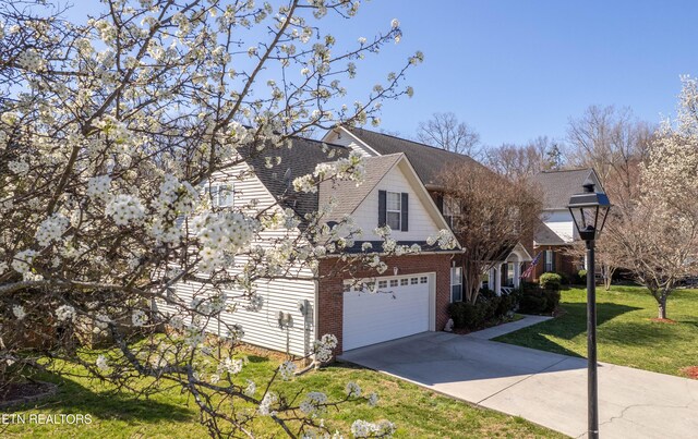 view of front of property with an attached garage, concrete driveway, a front yard, brick siding, and roof with shingles