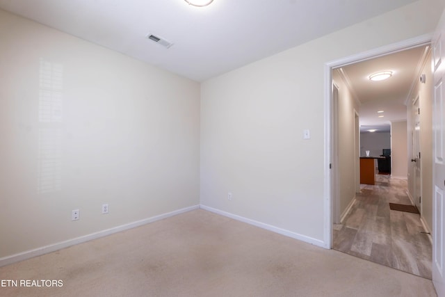 unfurnished room with baseboards, light colored carpet, and visible vents
