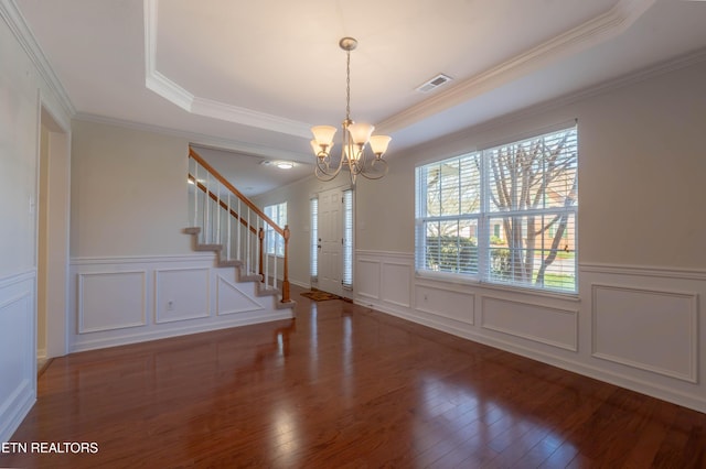 entrance foyer featuring a tray ceiling, stairs, an inviting chandelier, wood-type flooring, and visible vents