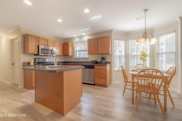 kitchen featuring an inviting chandelier, ornamental molding, stainless steel appliances, a center island, and a sink