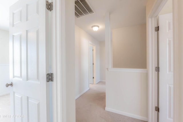 hallway with baseboards, carpet floors, and visible vents